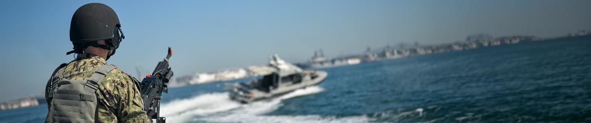Master-at-Arms 2nd Class Michael L. Kennedy mounts the M240b machine gun at the bow of a Scam Alerts: “Metal Shark” security boat during a simulated small boat attack drill. 